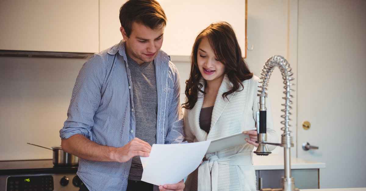 Kinetico Water Softener Cost Guide couple reviewing water bill and kitchen faucet at home scene area